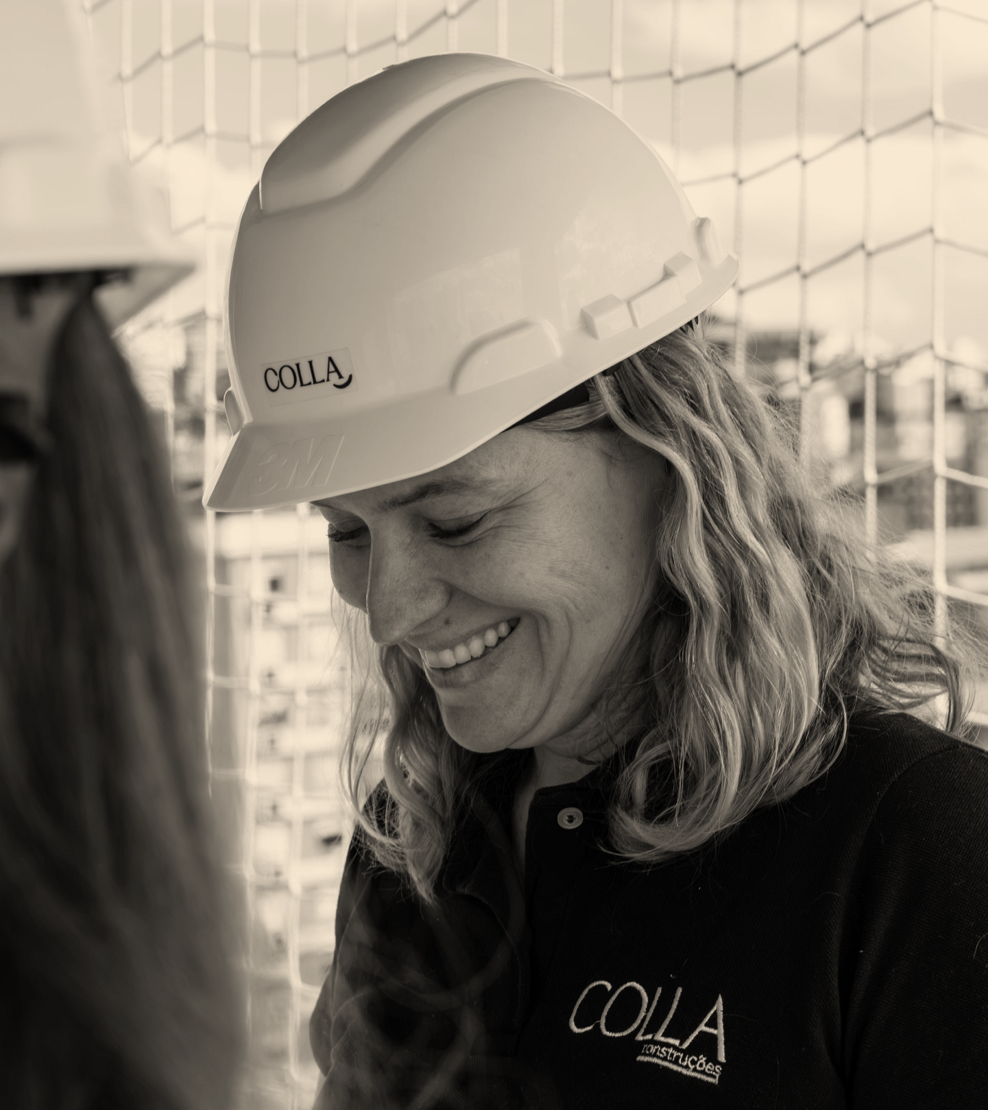 Arquiteta Letícia sorrindo e olhando para baixo, com destaque para o capacete com o logo Colla.