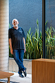 Retrato de Nereu, consultor imobiliário da Colla, diante de painel de vidro e vegetação.